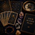 A styled flat-lay of tarot card deck components, crystals, a compass, and a black book titled 'YOUR ACTION PLAN' on a dark textured surface. The cards feature gold celestial illustrations on a deep navy background.